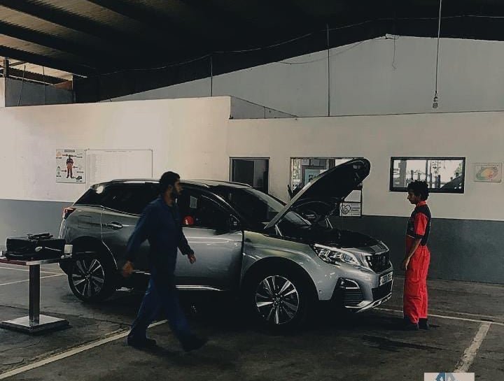 Vehicles and technicians in a workshop service bay
