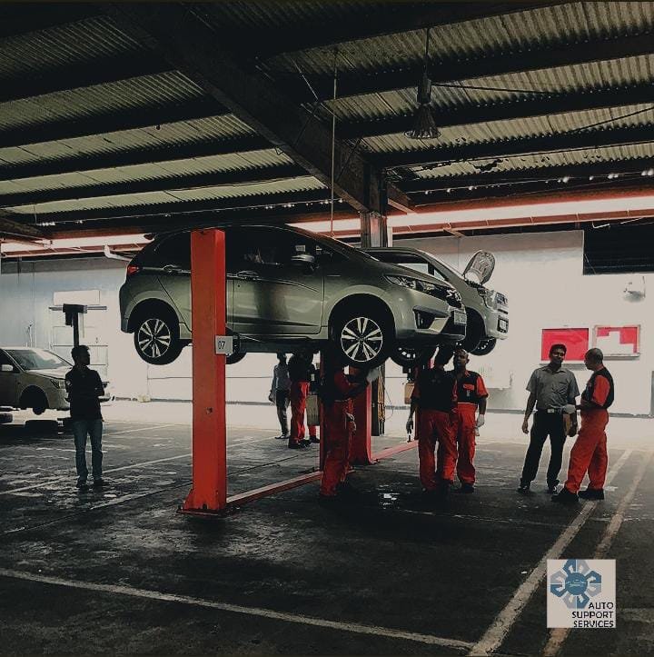 Technicians beside a raised vehicle in a workshop